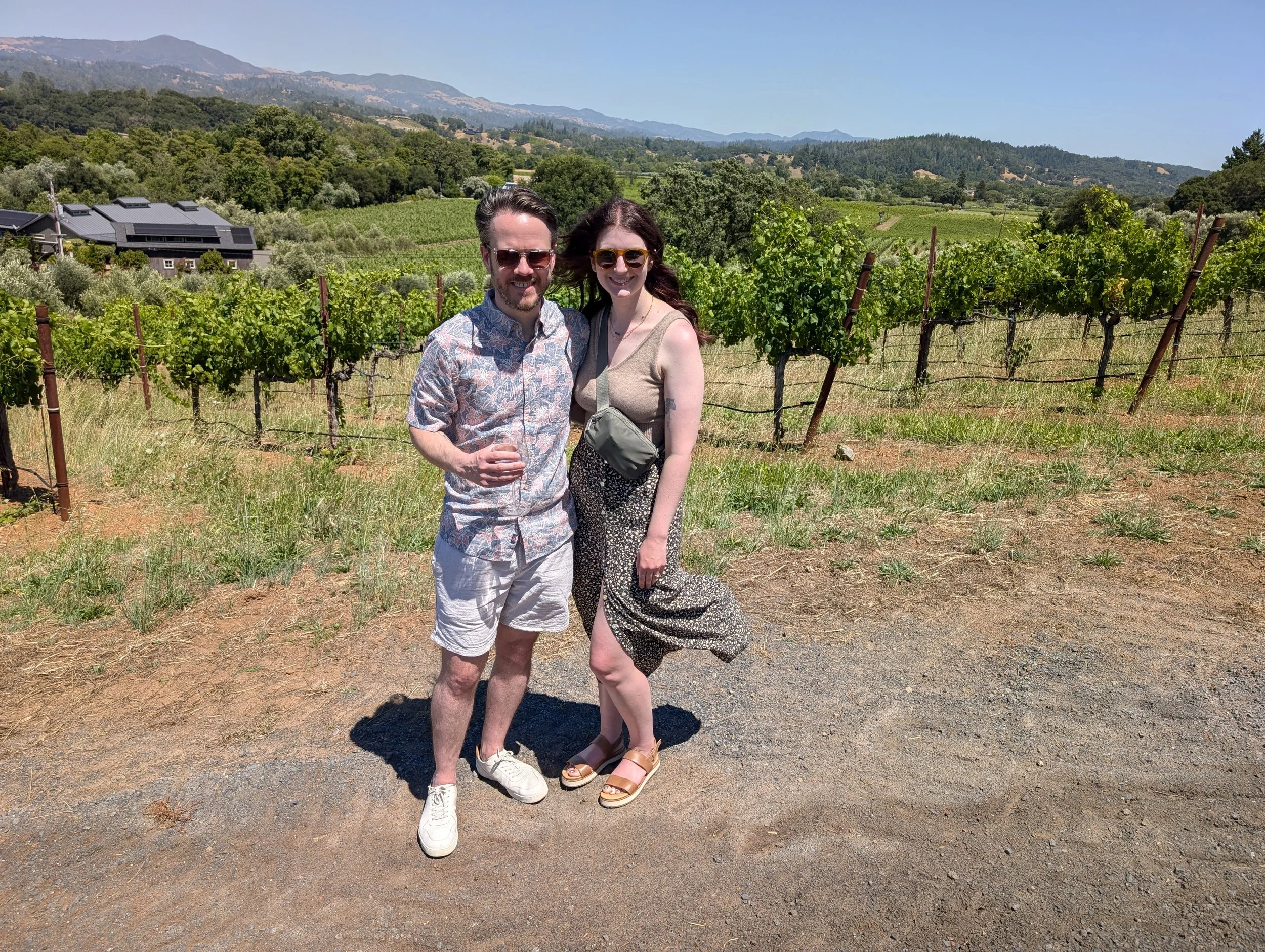A man and a woman standing in front of a vineyard at Bella Winery in Healdsburg, CA