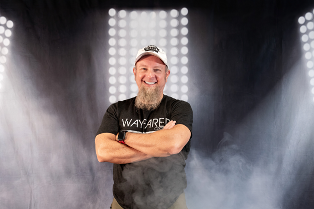 Eric Kulikowski with black Wayfarer CrossFit shirt on a smoke lights background. 