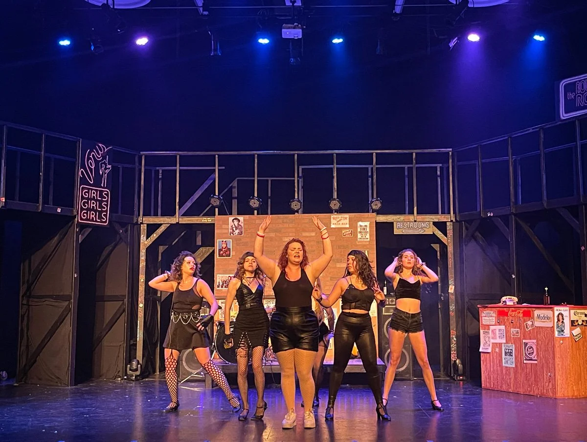 A theatrical stage scene with five women performing a dance.