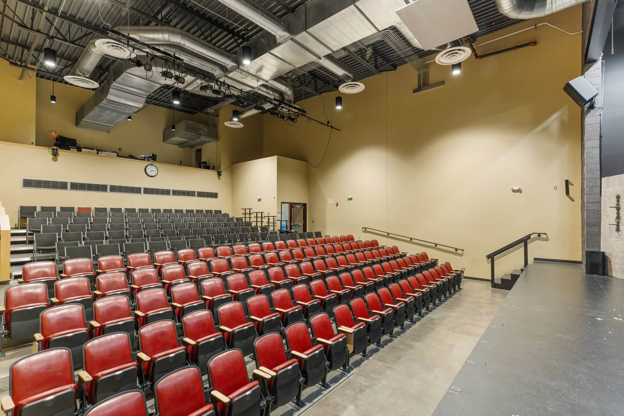 Empty auditorium with rows of red seats.
