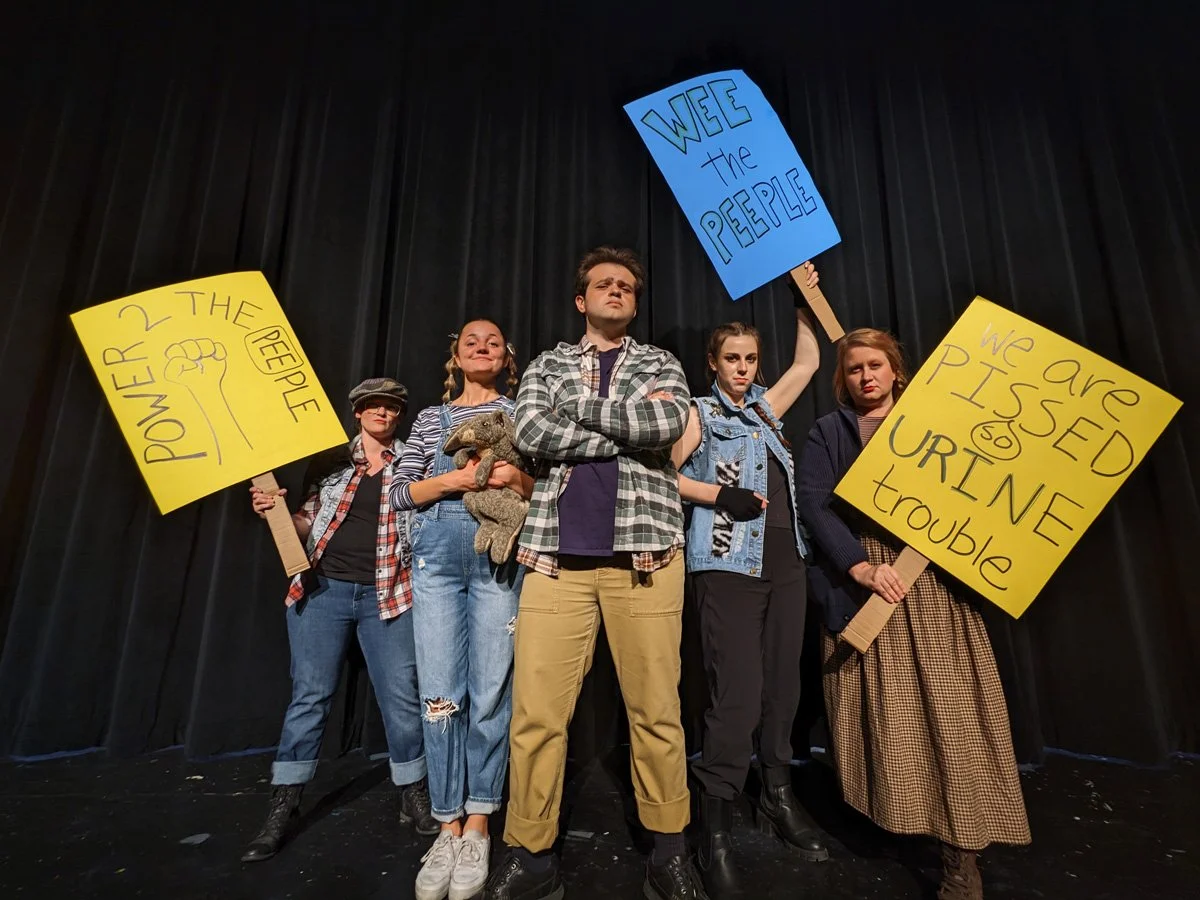Group of five people on stage holding protest signs.