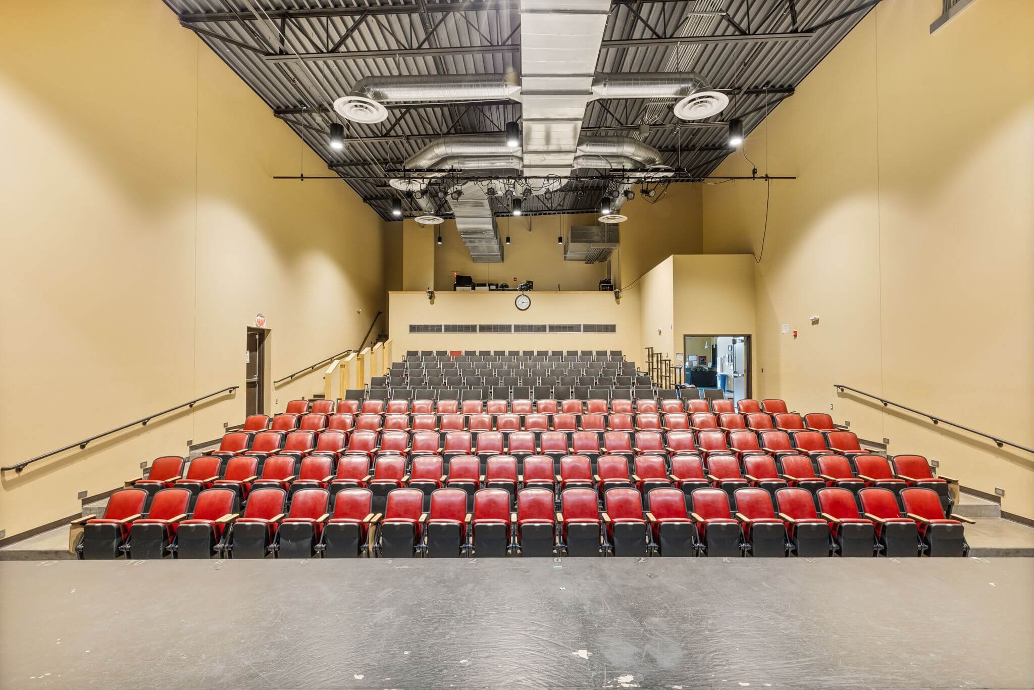 Auditorium theater seating with red chairs.