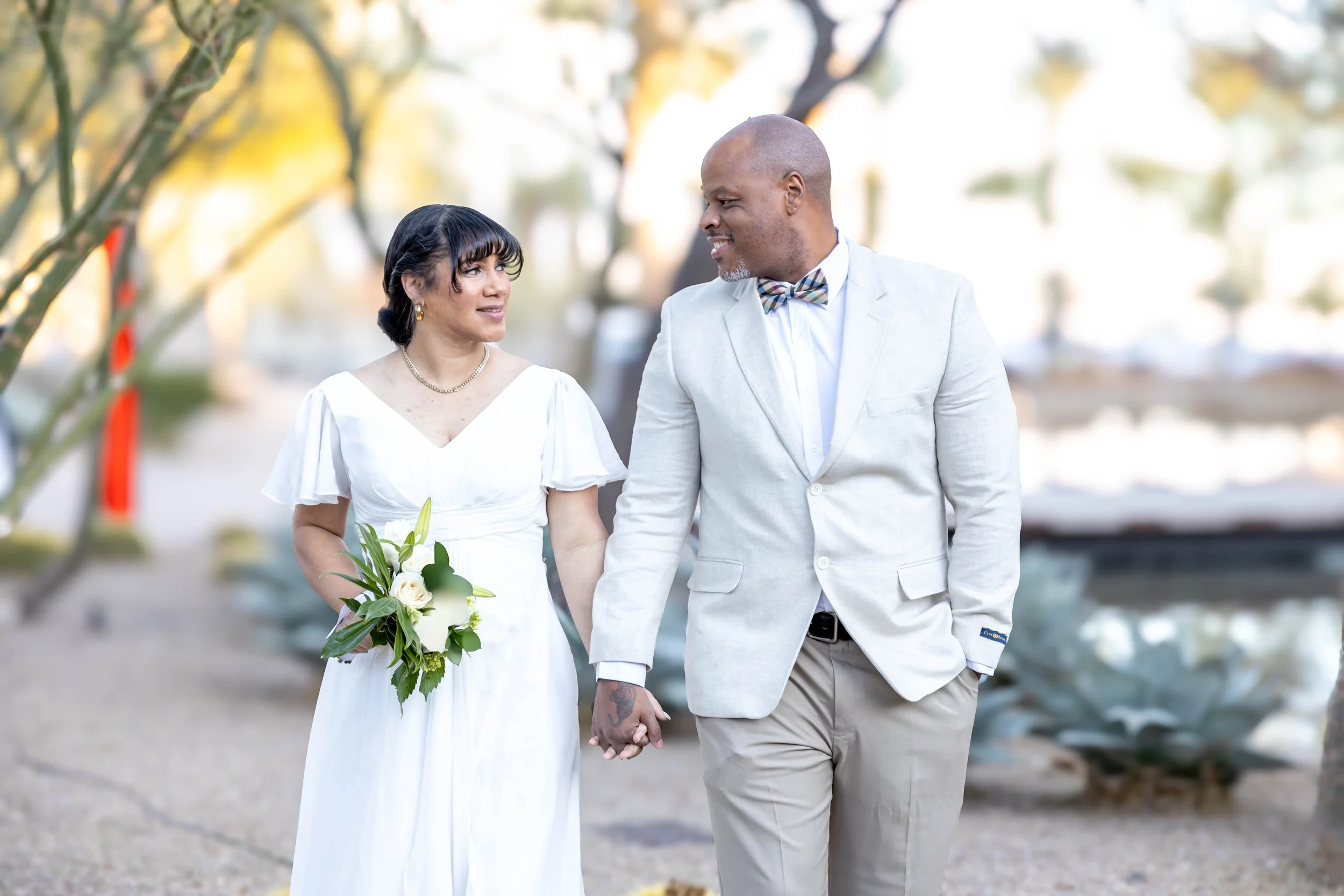 Laurie’s customers, Mariana and Carmen holding hands on a green lawn on their wedding day.
