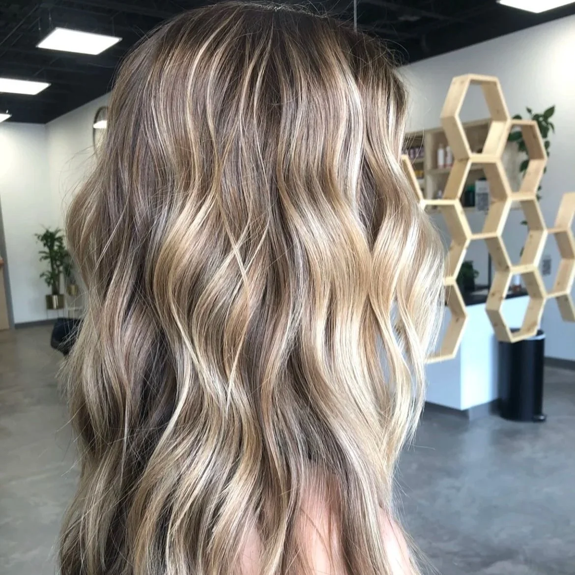 Woman with long, wavy blonde hair in a hair salon.