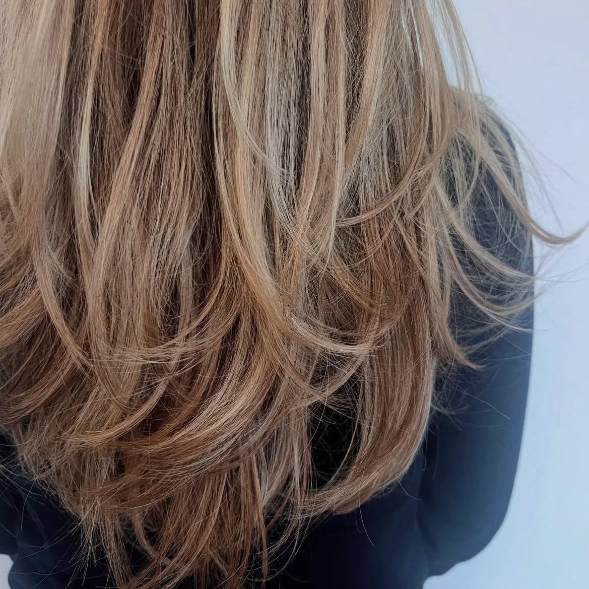 Close-up of wavy blonde hair with layered texture.