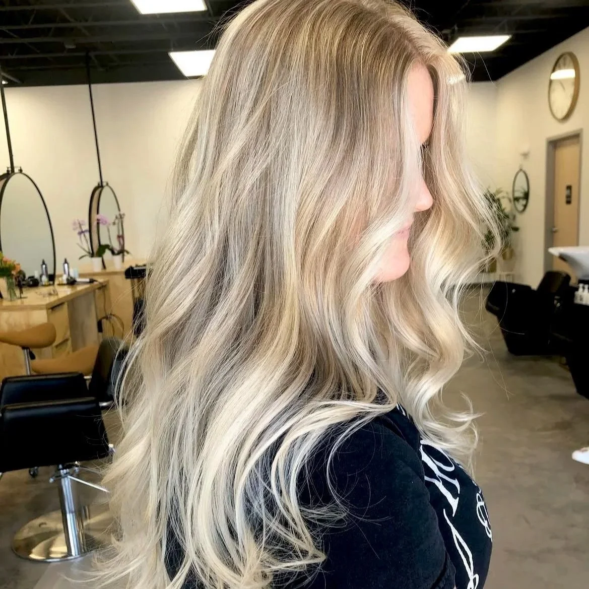 A woman with long, wavy blonde hair in a hair salon.
