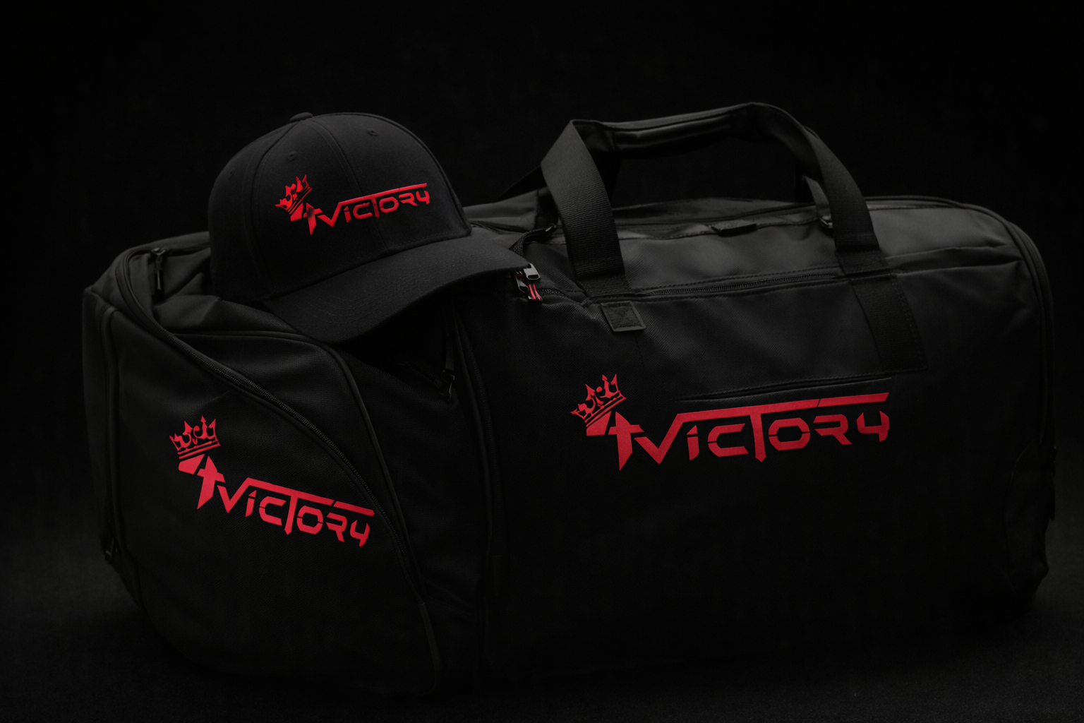 Sac de sport noir avec logo rouge Victory et casquette assortie aussi portant le logo en rouge, tout sur un fond noir.