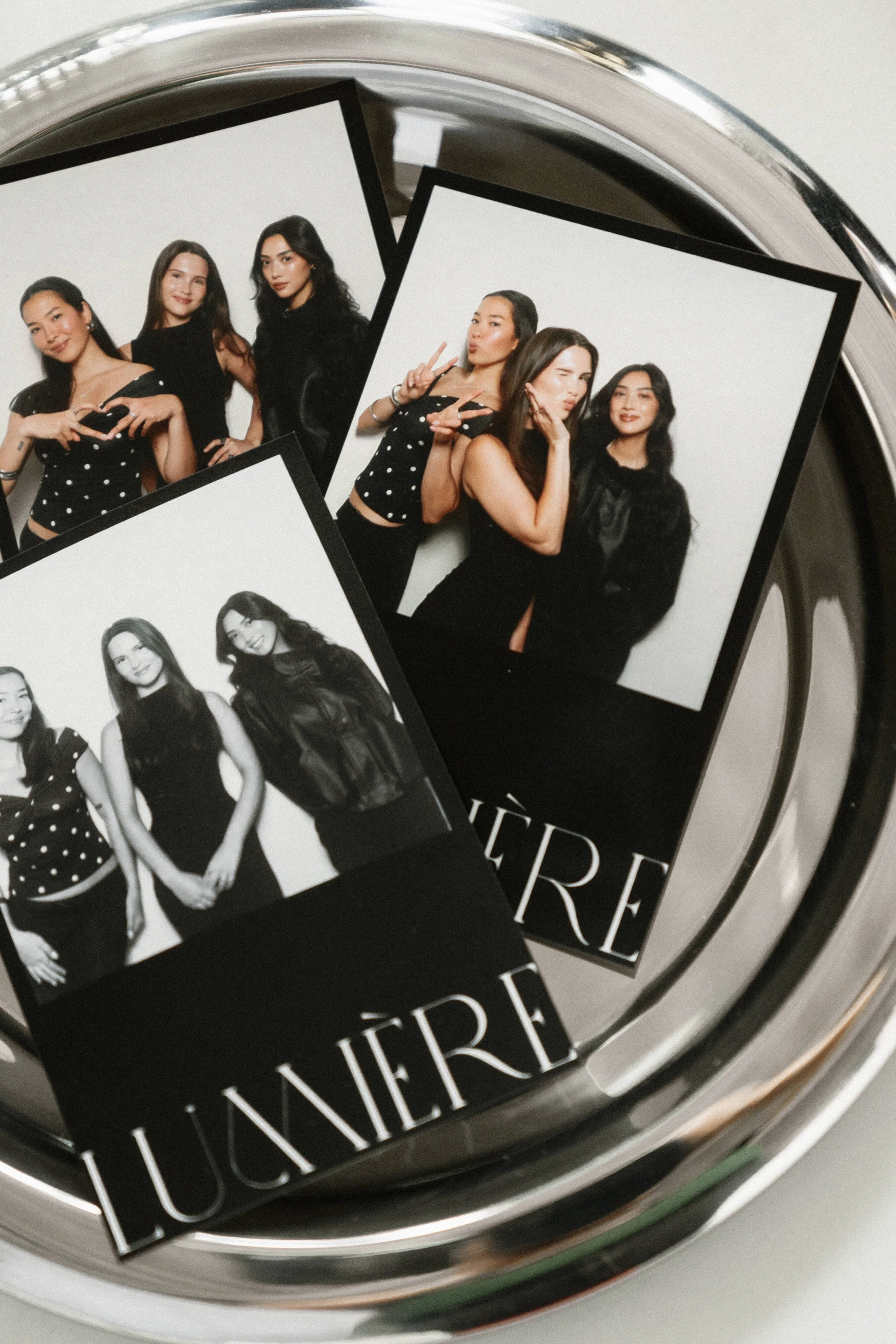 Close-up of a round mirrored surface with printed photos of five women, including one black-and-white photo, and part of a black and white label with the word 'LUNIVER' visible.