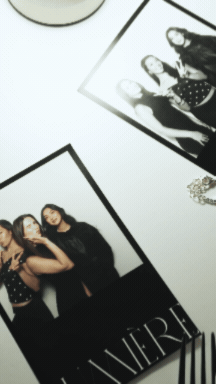 A collection of printed photographs and jewelry on a white surface, including a group of women in fashionable clothing.