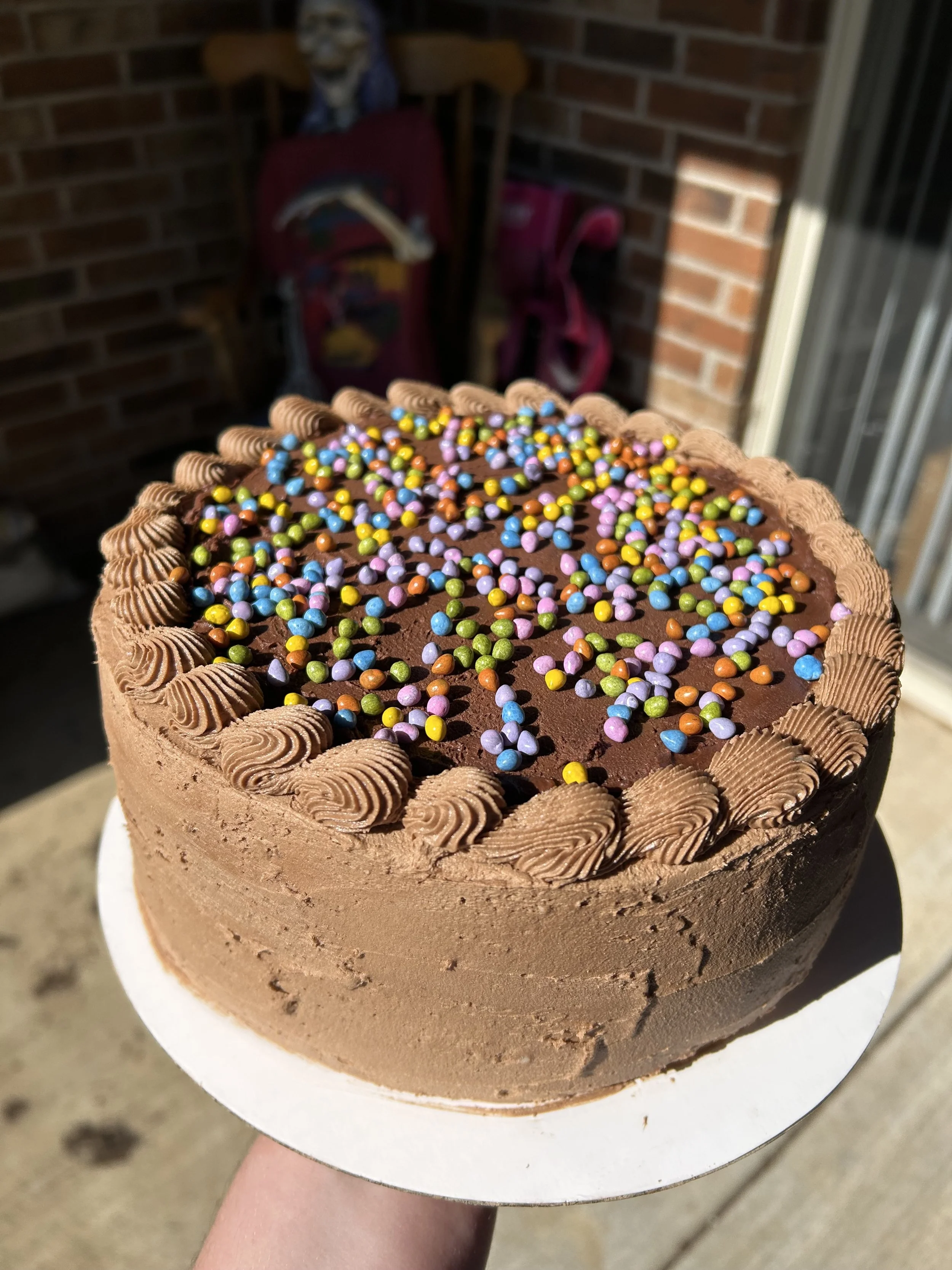 galaxy brownie cake. two layers of chocolate cake and buttercream with a chocolate ganache and sprinkle covered brownie in the middle and more ganache and sprinkles on top. rich and decadent.