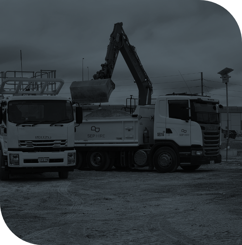 Construction site with two white trucks and a large excavator unloading dirt.