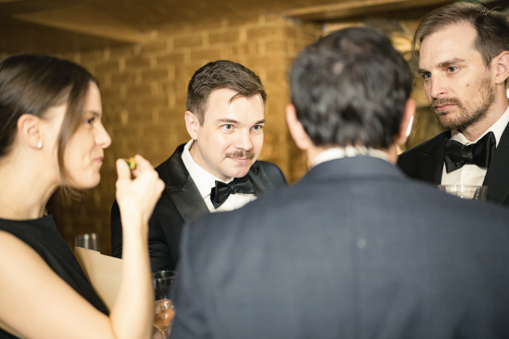 Four adults in formal attire engaged in conversation at a social event.