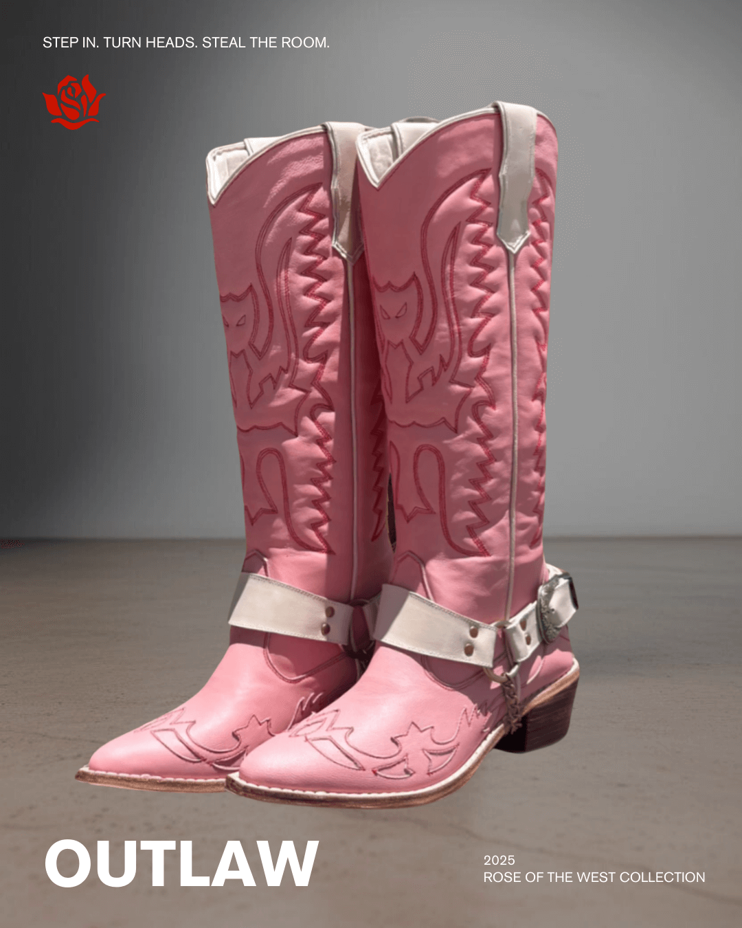 Pink cowboy boots with red embroidery and a white strap around the ankle, displayed against a gray background.