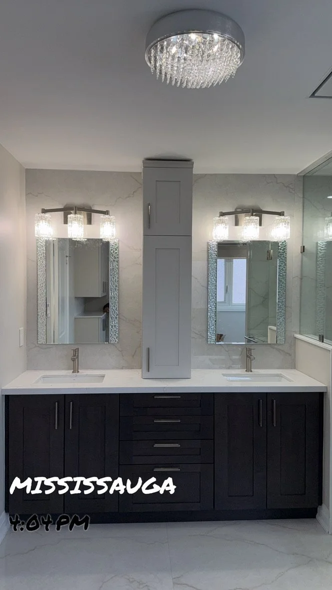 Modern bathroom with double sinks, two rectangular mirrors, chandeliers, and a central storage cabinet, with the word Mississauga and the time 4:04 PM written in the bottom left corner.