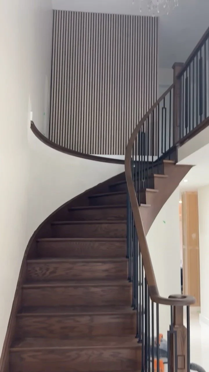 A wooden spiral staircase with black metal railing inside a modern home.