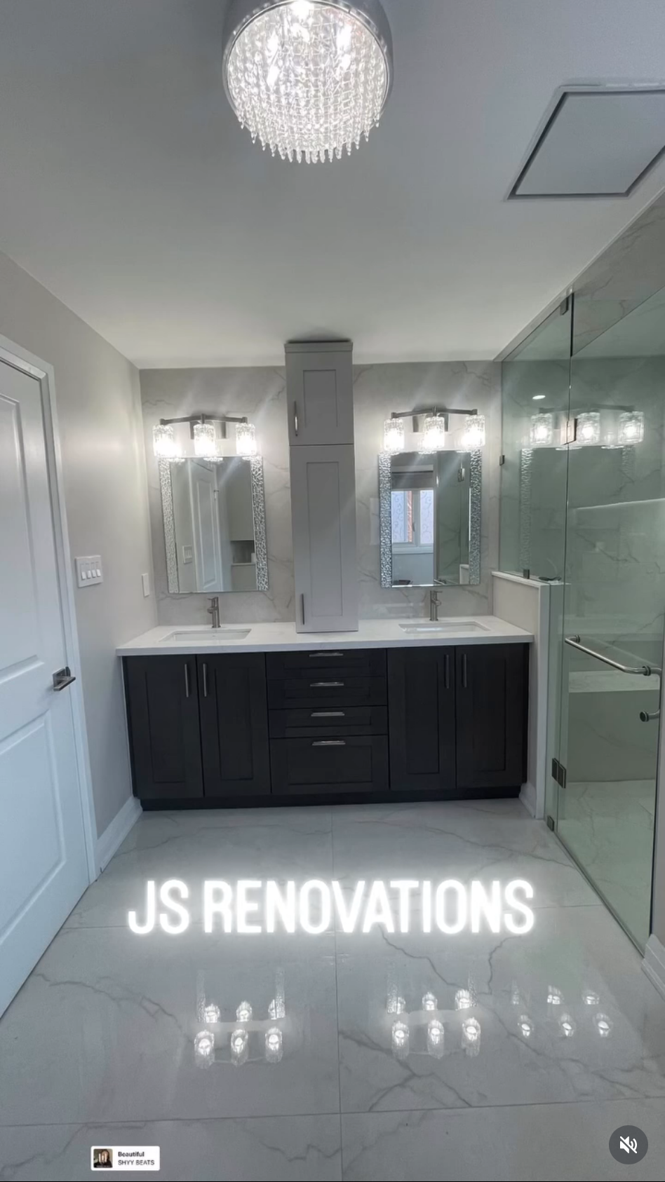 Modern bathroom with dual sinks, marble countertops, mirrored mirrors, and a glass-enclosed shower; brand text 'JS RENOVATIONS' at the bottom.