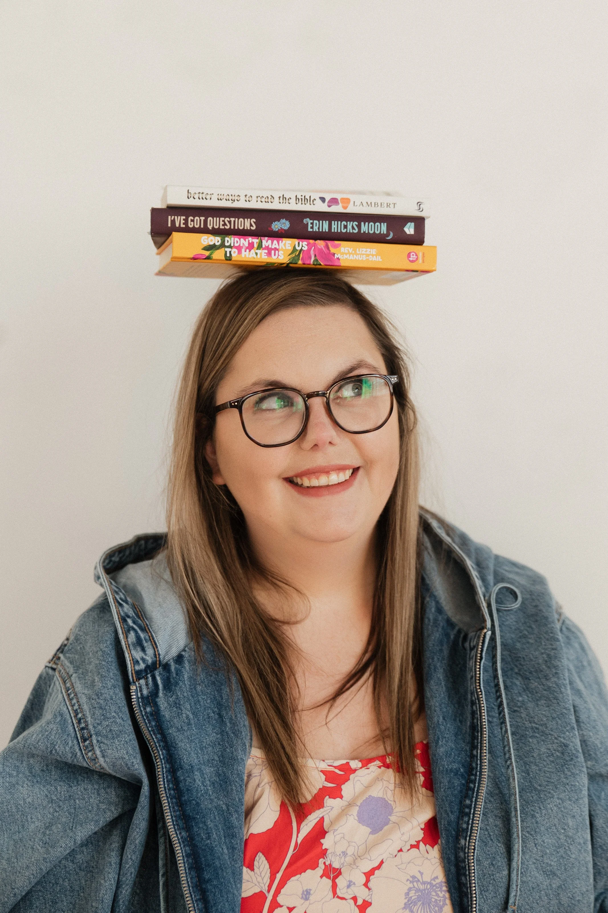 Girl with glasses has books on her head