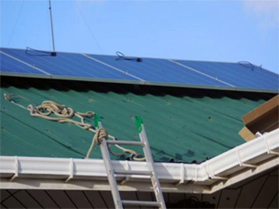 Solar panels installed on a roof with a ladder and climbing equipment nearby.