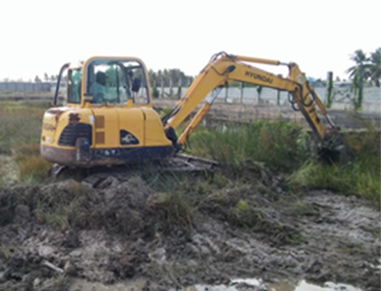 A yellow Hyundai excavator working in a muddy construction site.