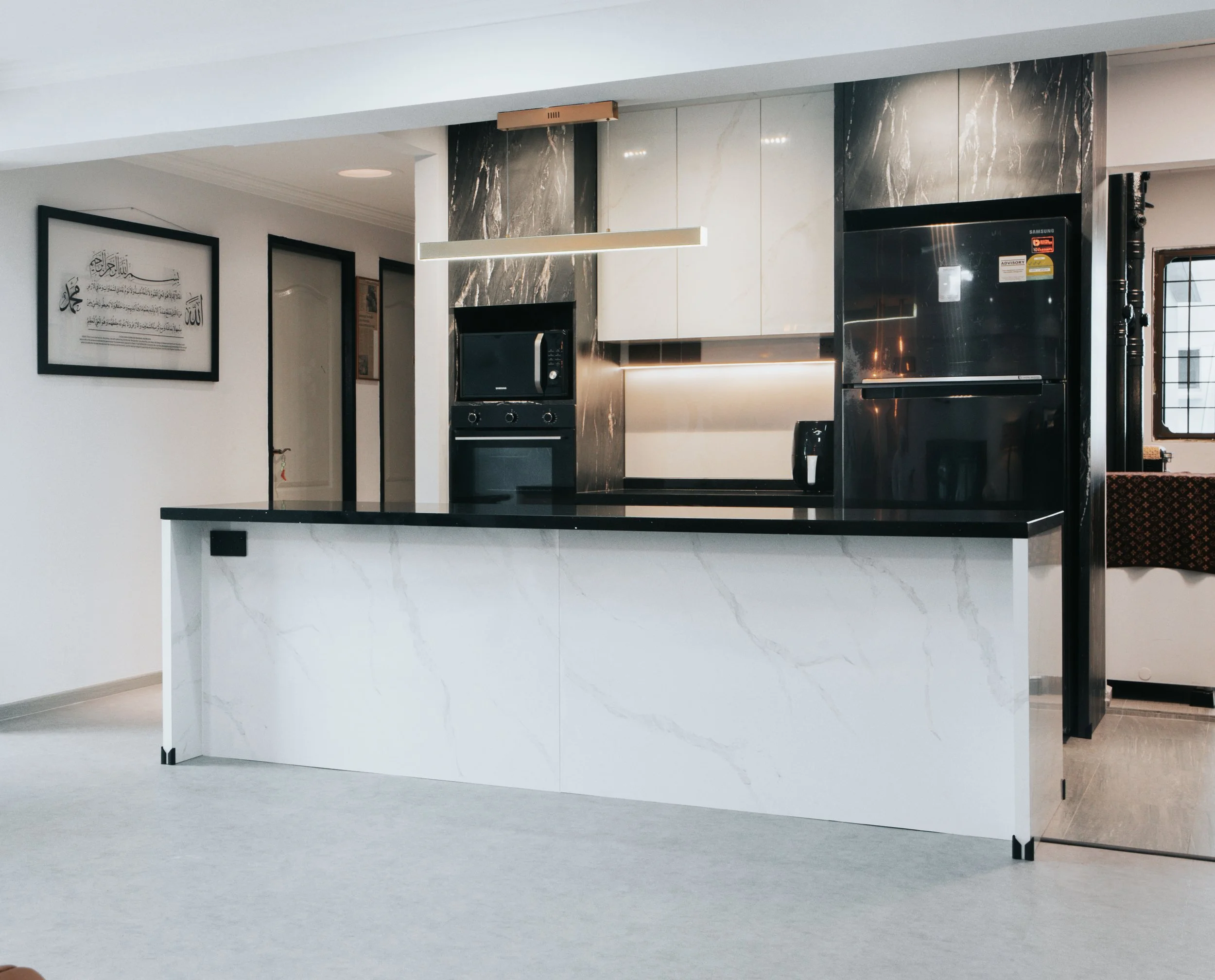 Sleek modern kitchen with black cabinets and marble countertops, featuring a central island and stainless steel appliances.