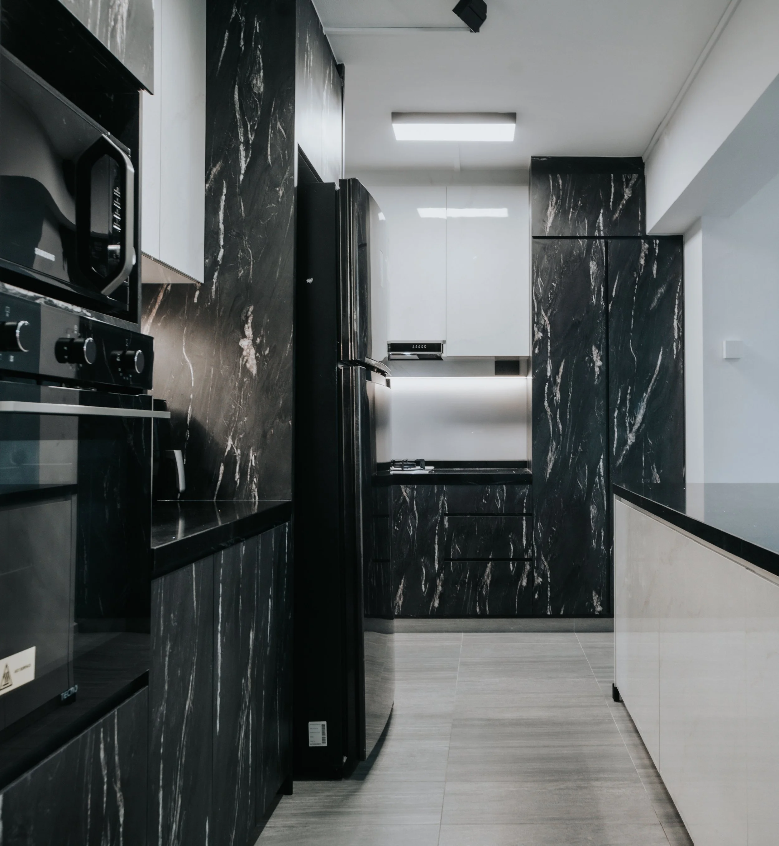 Sleek modern kitchen with black marble countertops and cabinetry, featuring stainless steel appliances and a minimalist design.
