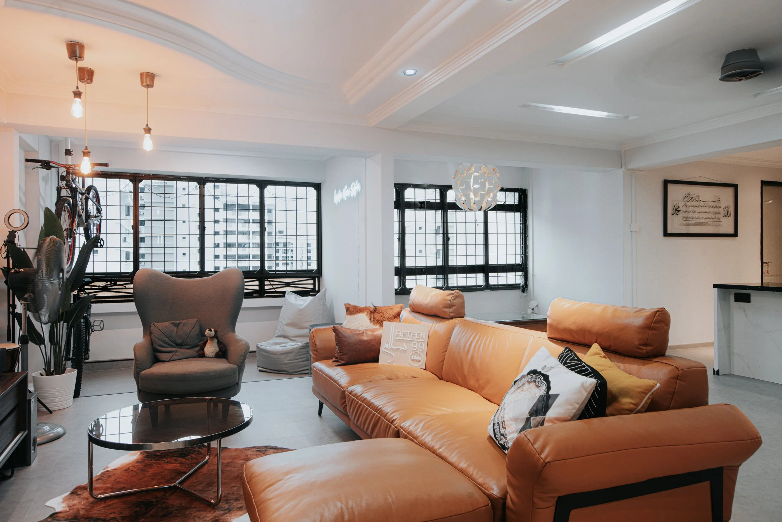 A modern living room featuring a leather sofa, round coffee table, and large windows with natural light.