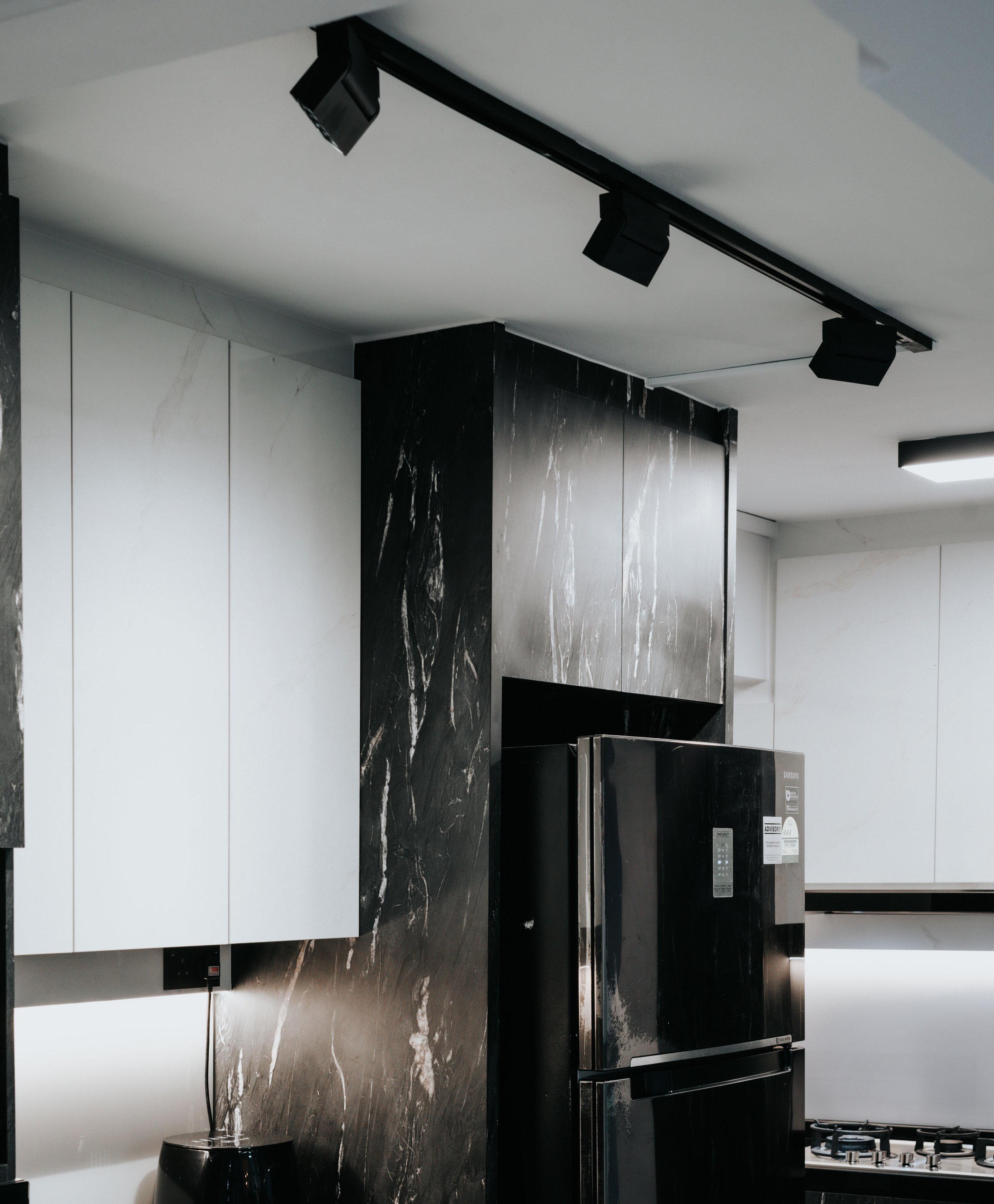 Sleek modern kitchen featuring black appliances and white cabinetry with marble accents.