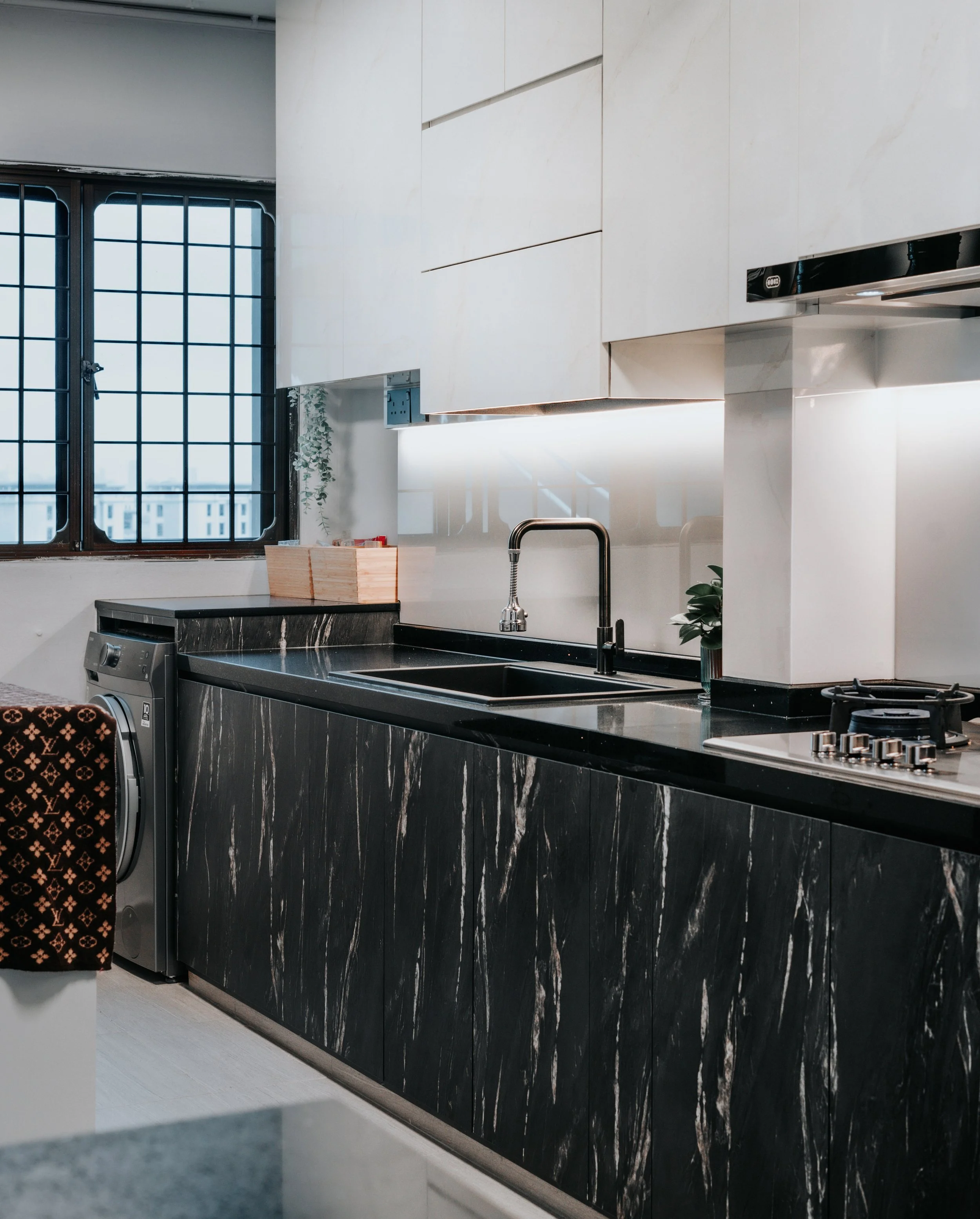 A modern kitchen featuring a black marble countertop and sleek cabinetry, with a window providing natural light.