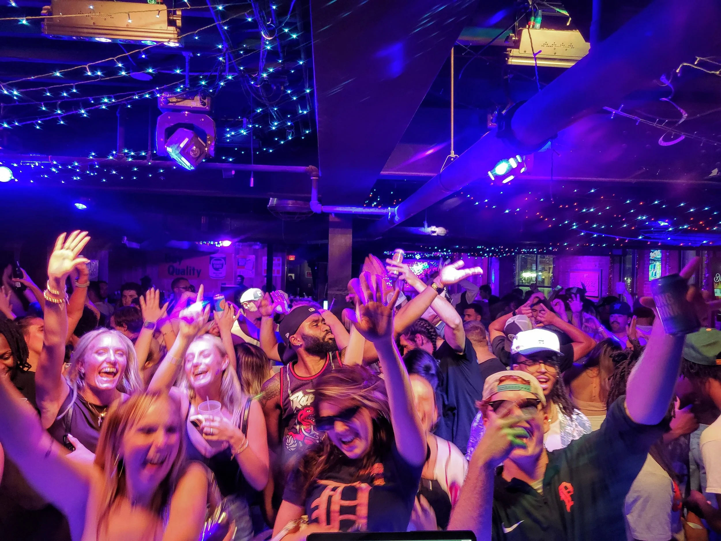 People dancing and enjoying music at a lively dance club with colorful lights and a festive atmosphere.