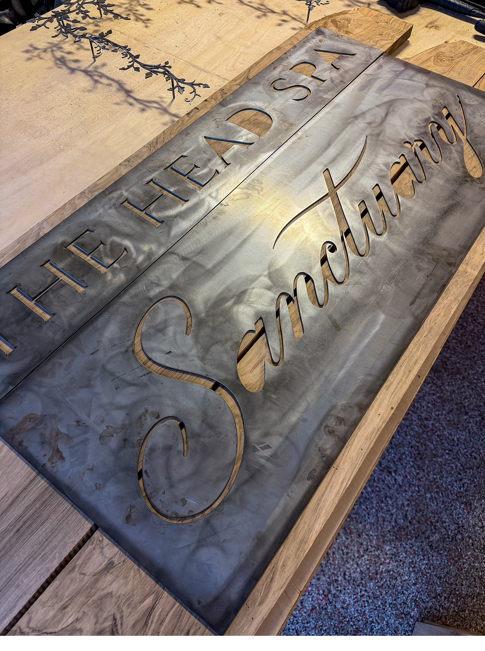 Metal sign on a wooden table with the words "HEAD SPA" and another word that is partially visible, with a decorative element above the sign.