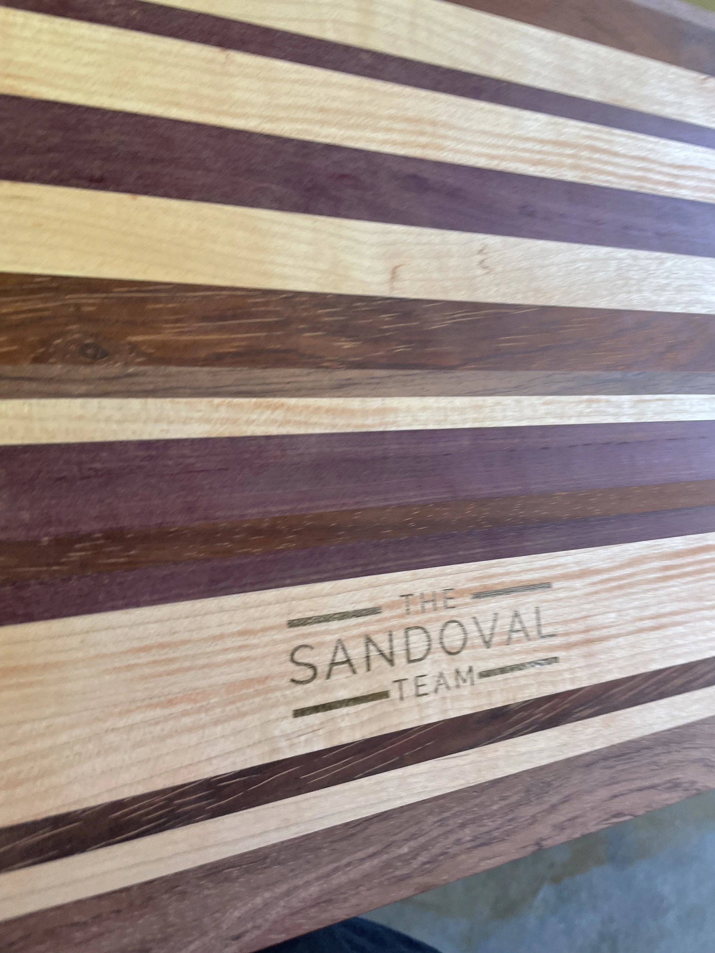 Close-up of a wooden tabletop with engraved text that reads 'THE SANDOVAL TEAM'.