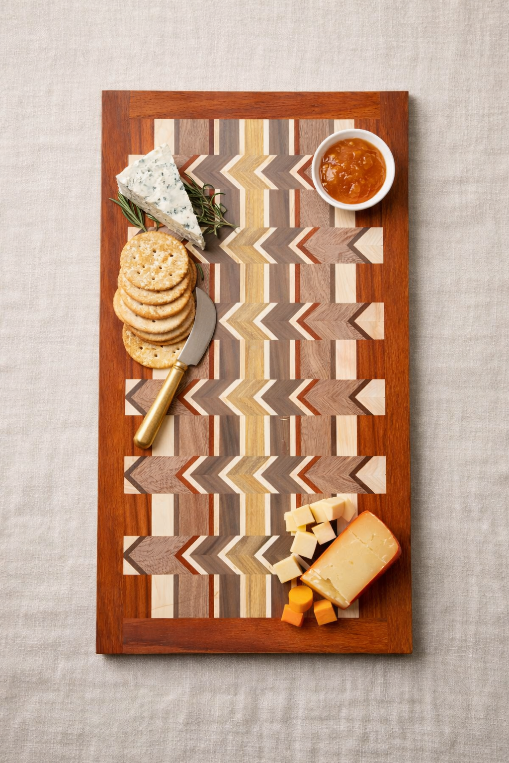 Cheese and crackers on a decorative wooden cheese board with a cup of jam.