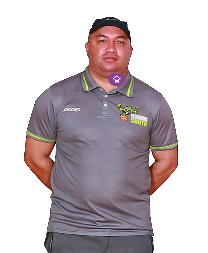 A man standing with his hands behind his back, wearing a gray athletic shirt with green accents, a black baseball cap, and a black shirt underneath. The shirt has a logo with a cartoon lizard holding a basketball and the text "TRUGANINA SOUTH" on the front.