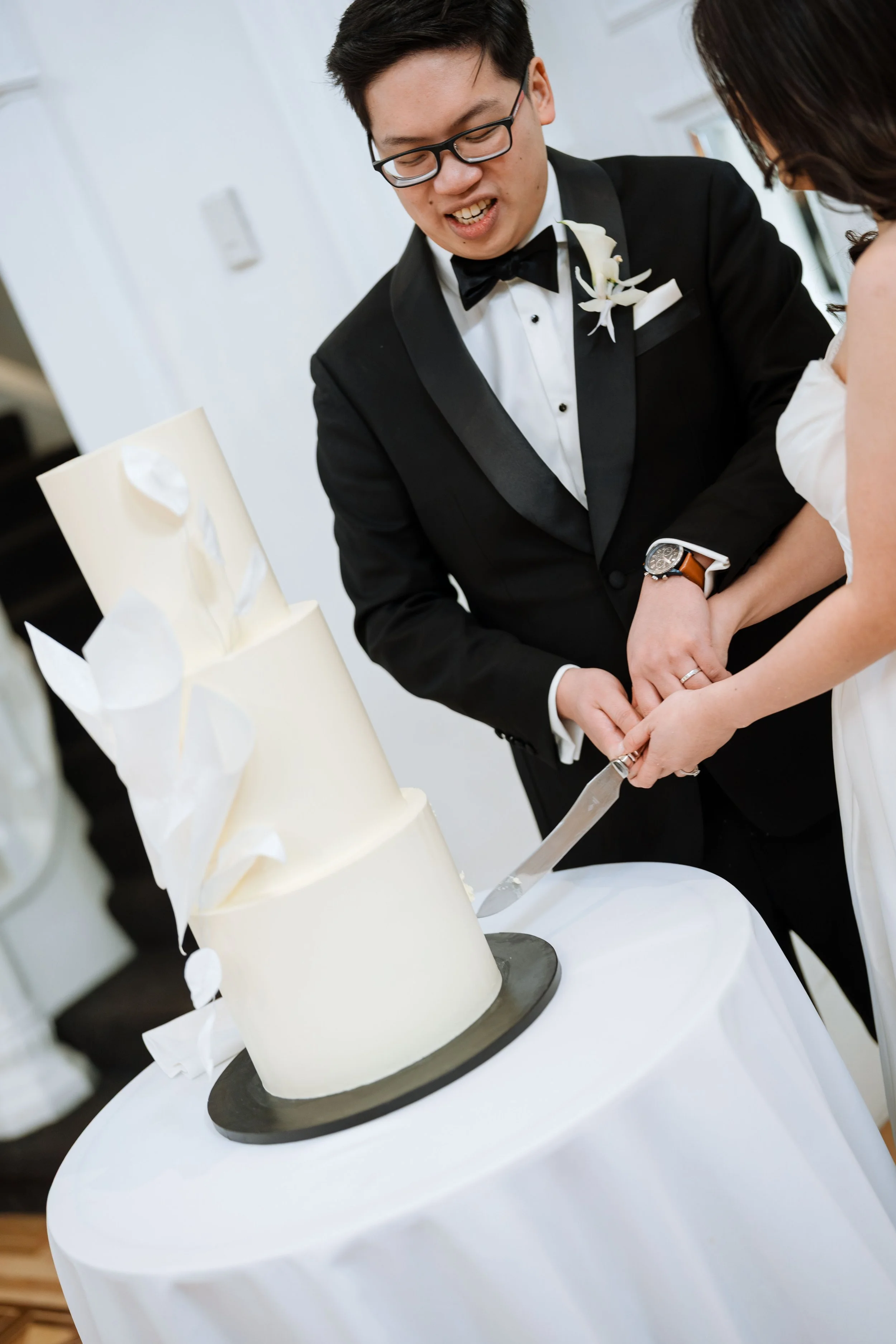 A newlywed couple cuts a wedding cake together during their wedding reception.