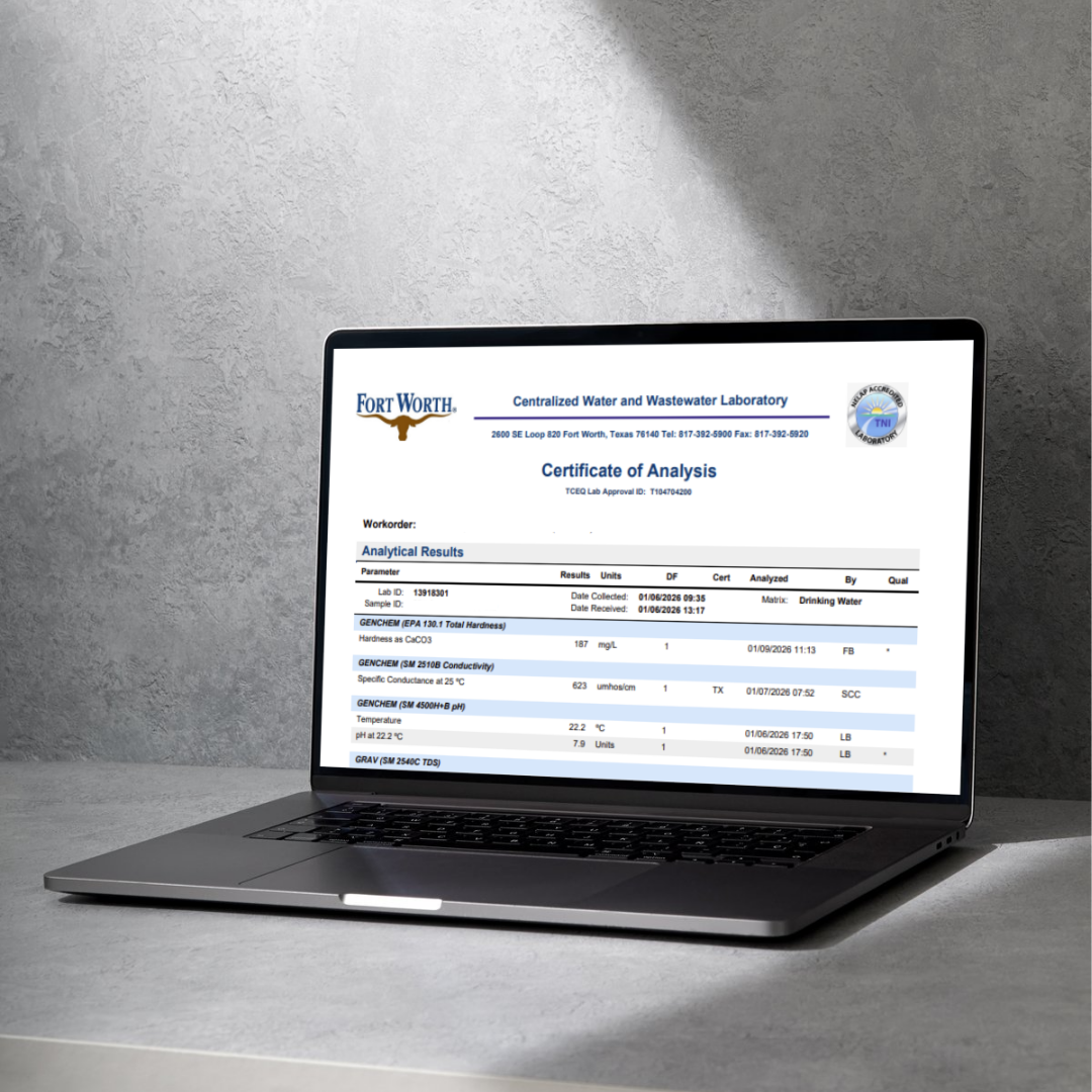 Laptop displaying a laboratory report titled 'Certificate of Analysis' for drinking water at Fort Worth Centralized Water and Wastewater Laboratory, with data on water hardness, conductivity, pH, and TDS.