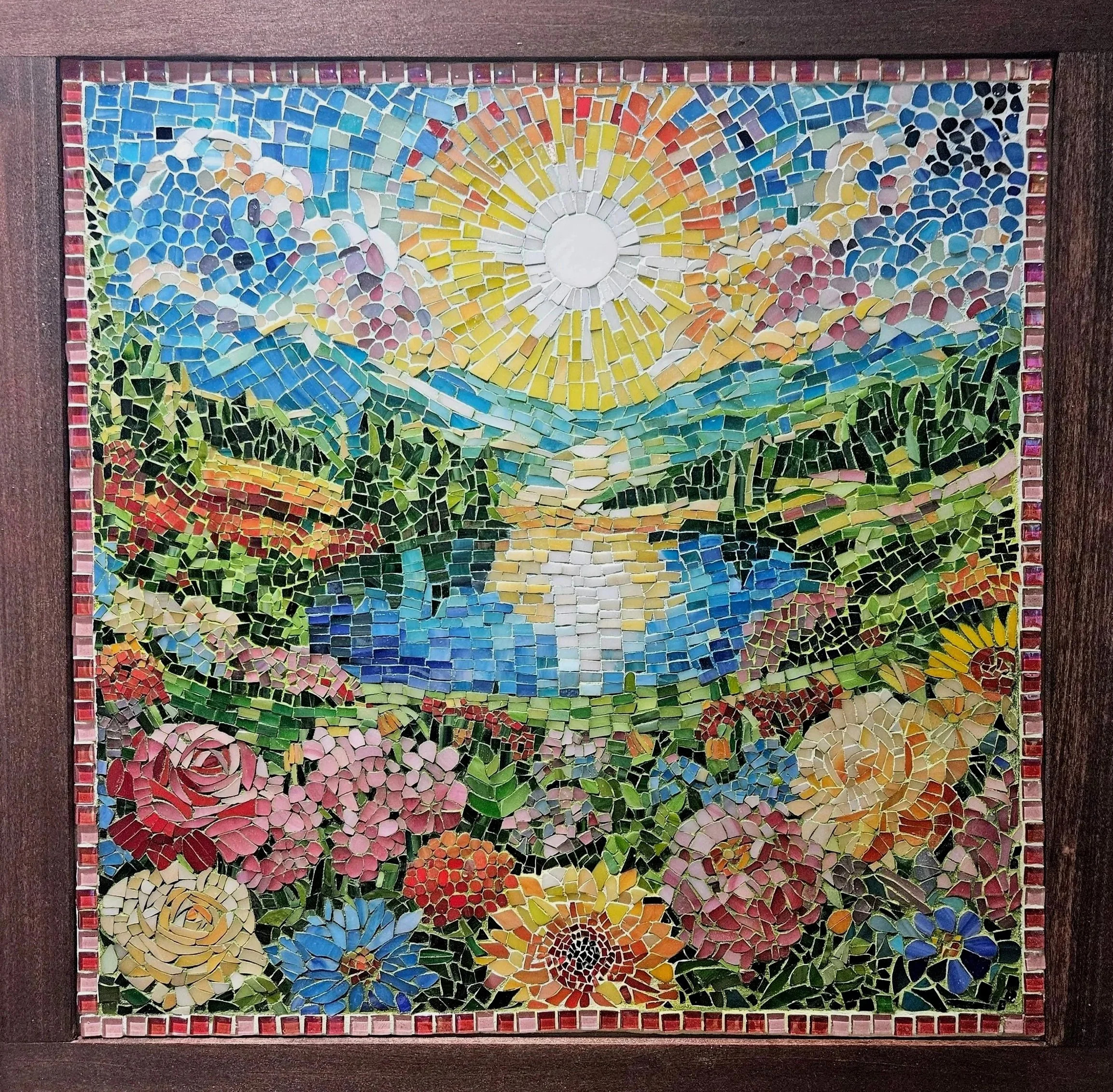 Colorful mosaic art depicting a bright sun, mountains, trees, a lake, and flowers.