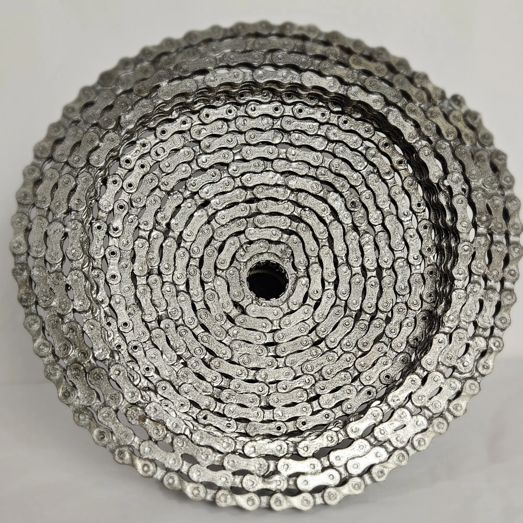 Close-up of a coiled silver bicycle chain, viewed from the end.