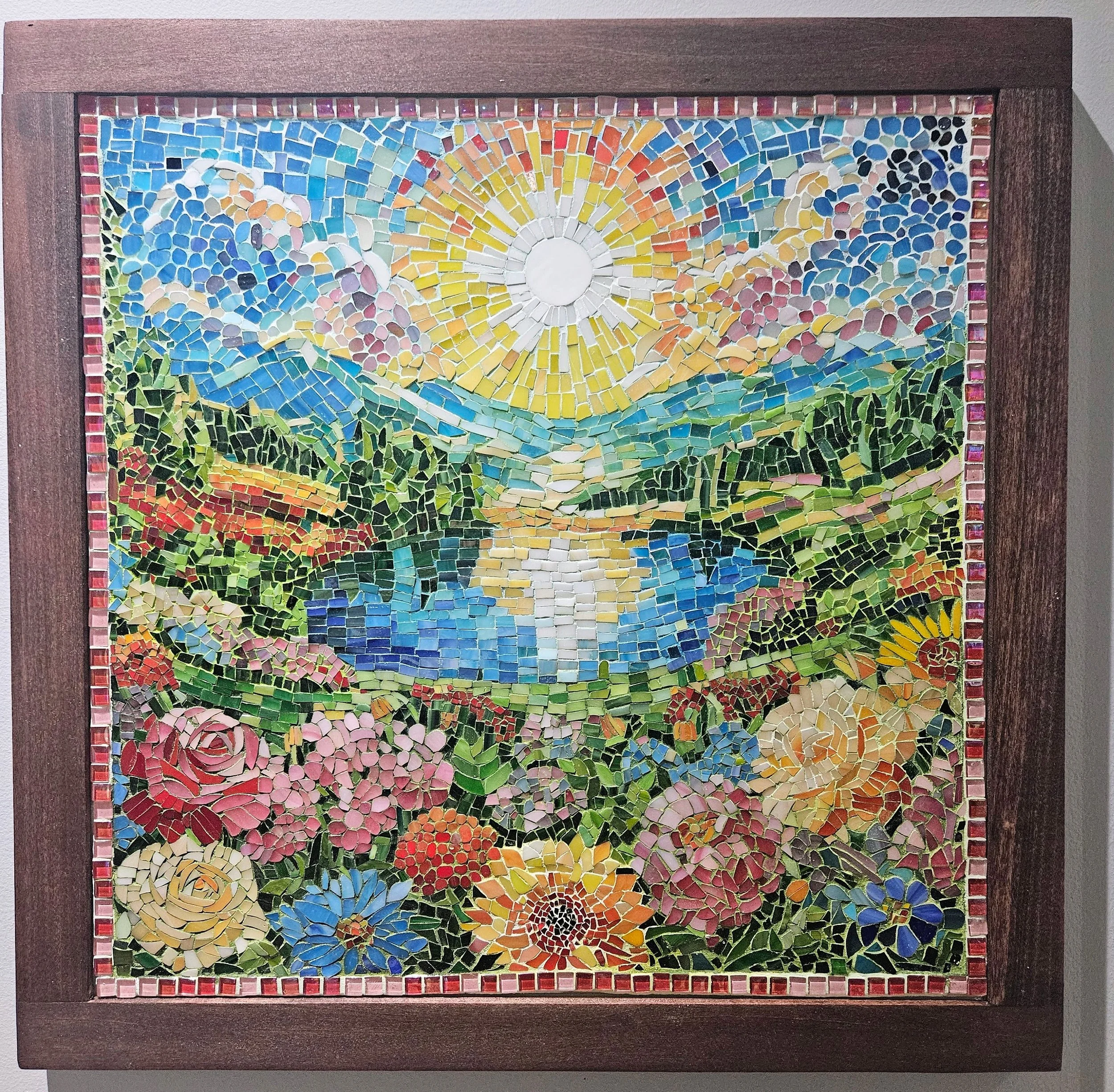 Photo of mosaic artwork featuring a sunrise over a lake and foreground flowers.