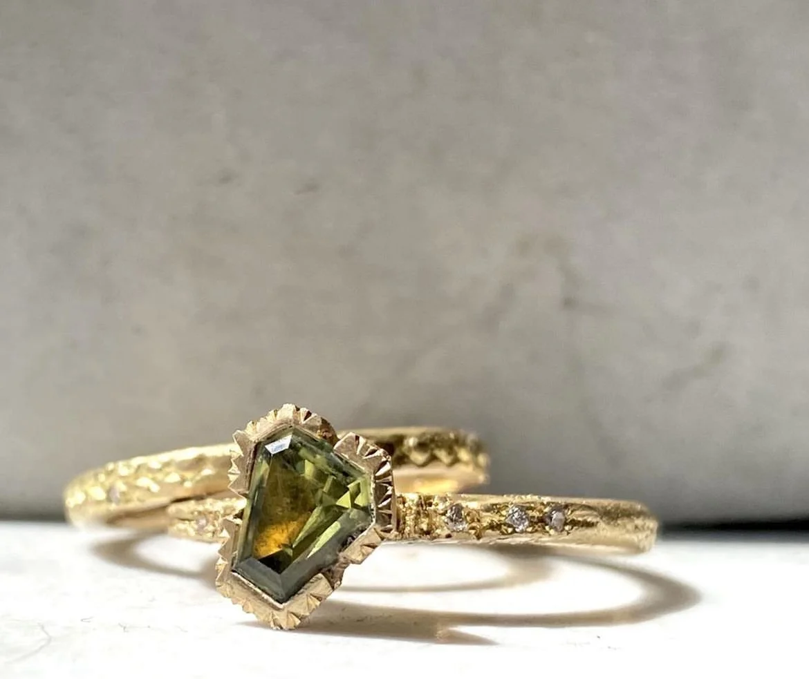 Gold ring with a greenish rectangular gemstone and small surrounding diamonds