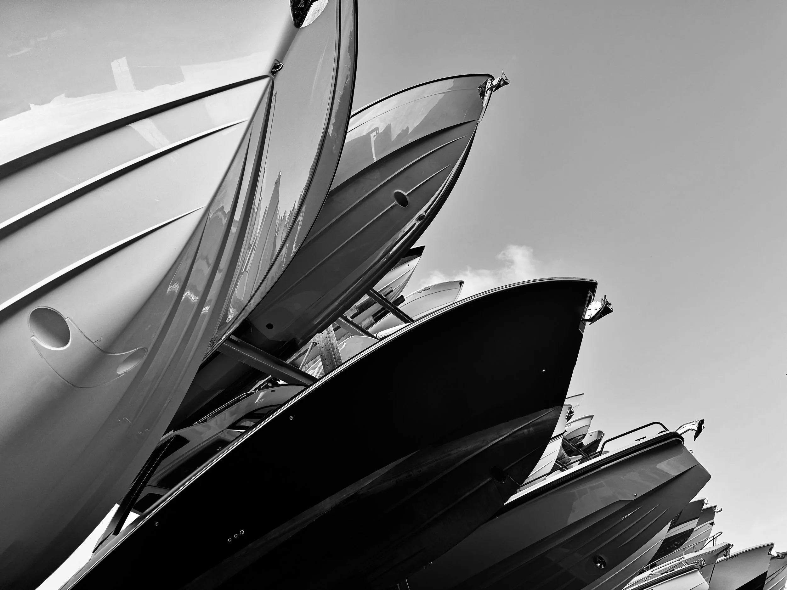 A row of boats stacked on top of each other, seen from below against a cloudy sky.