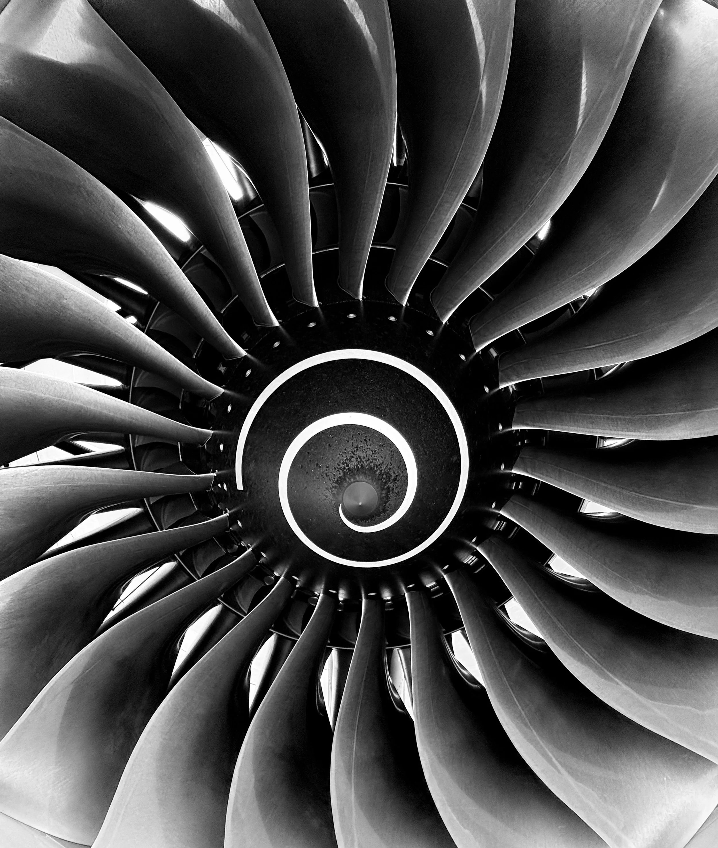 Black and white photograph of a circular spiral staircase viewed from above, highlighting the curved steps and central spiral pattern.