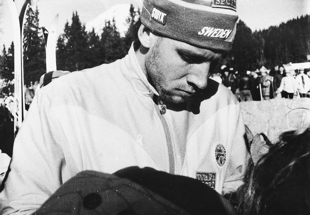 Torgny Mogren, Swedish cross country skier wearing a beanie with, surrounded by people outdoors in a snowy area.