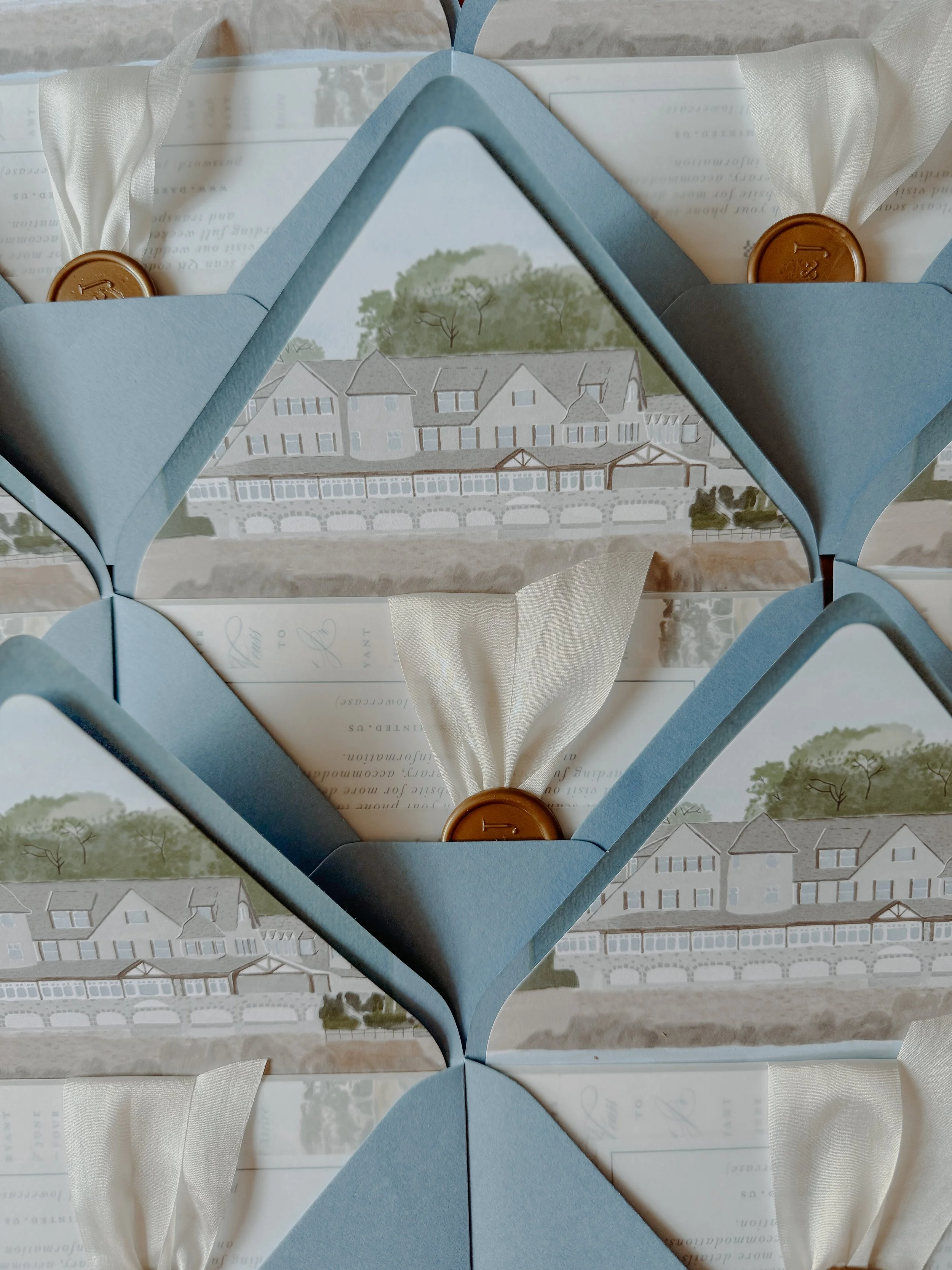 Multiple blue boxes with white ribbons and brown wax seals, each containing an invitation with a scenic illustration of houses and trees, arranged in an overlapping pattern.