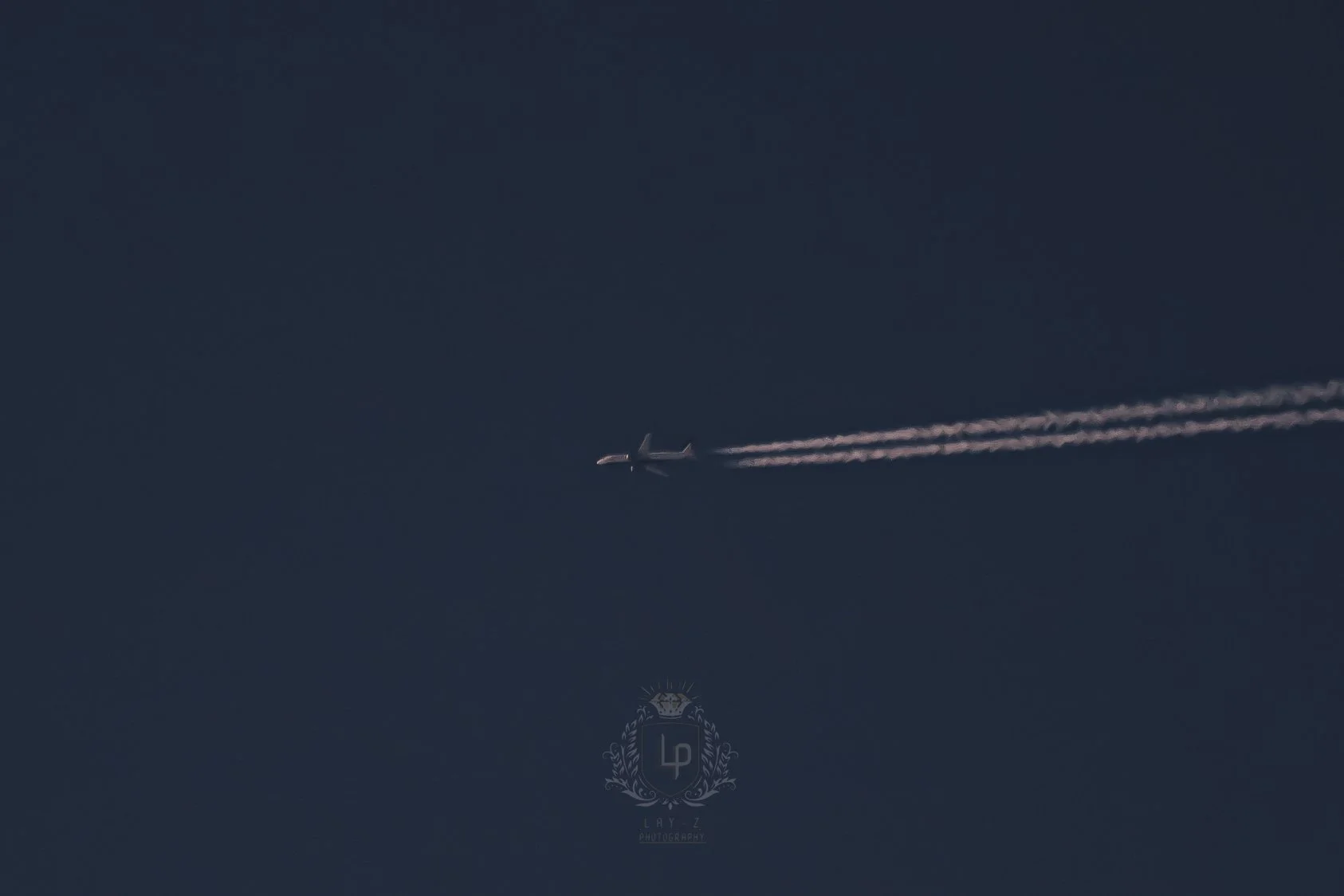 An airplane flying across the sky leaving a contrail trail behind.