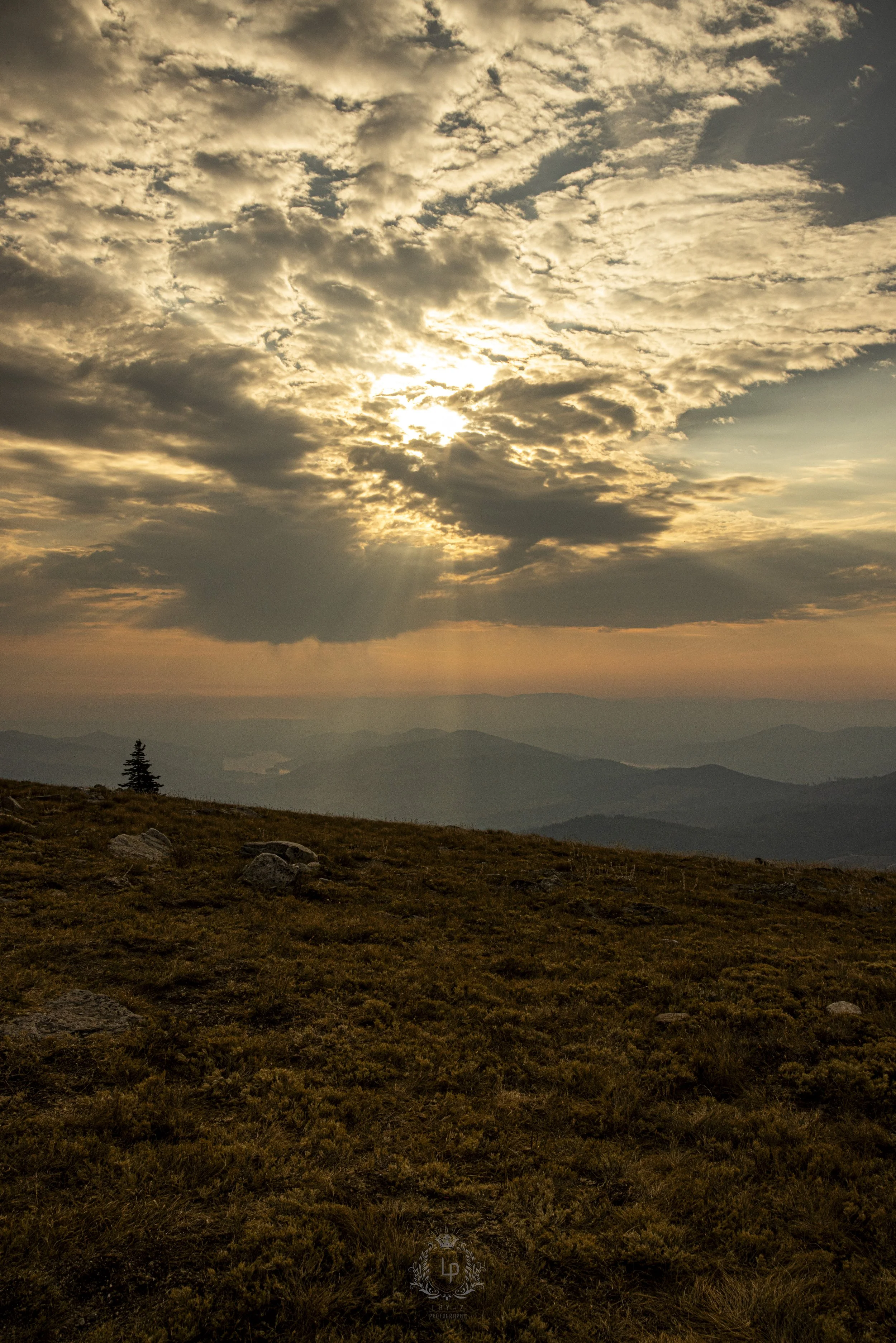 Sunset over a mountainous landscape with clouds in the sky.