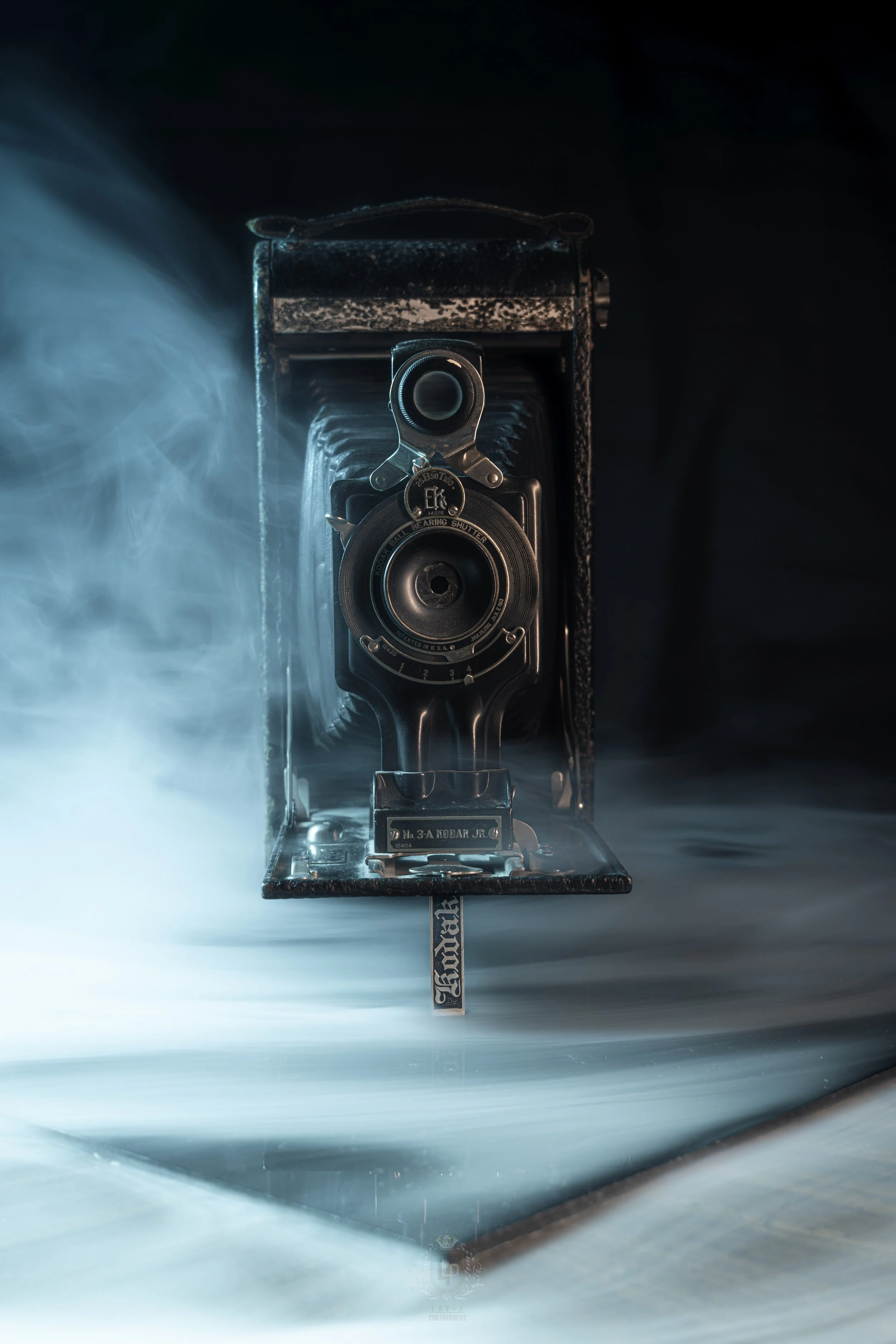 Vintage camera inside an open case with smoke or fog effects and dramatic lighting.