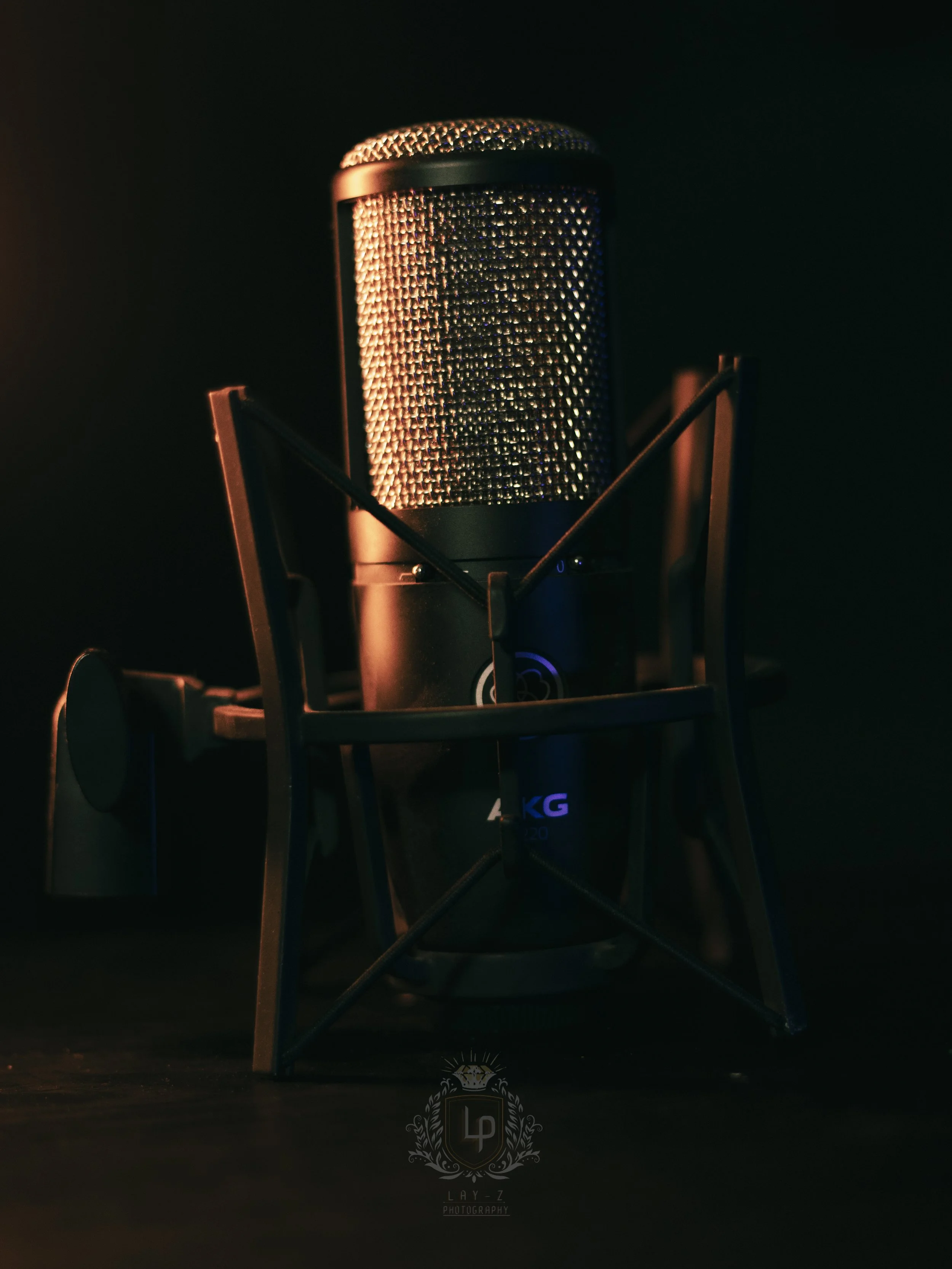 Studio microphone on a stand, illuminated with warm lighting, dark background.