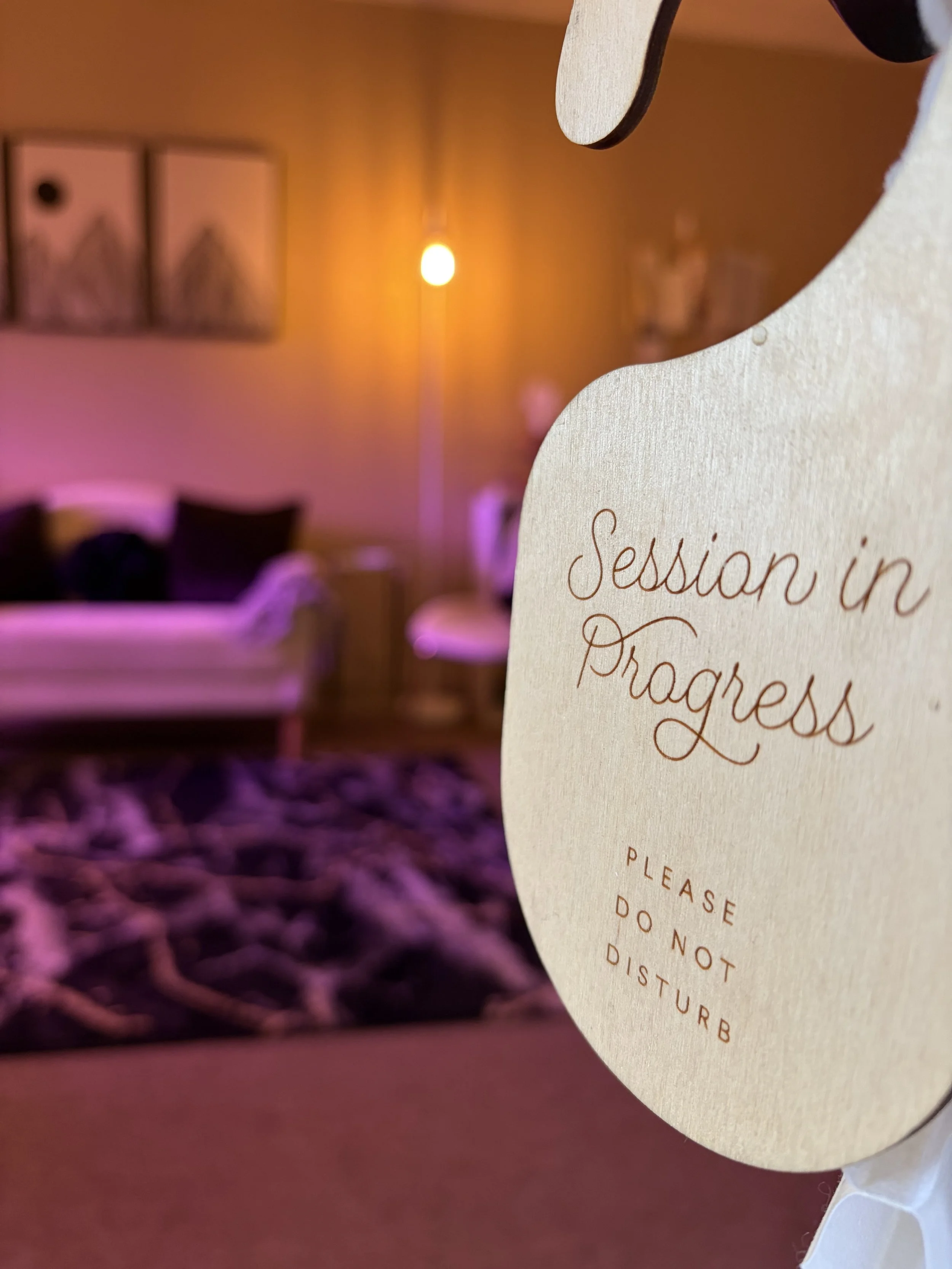 Therapy in session, please do not disturb sign hanging in front of a therapy office with modern furniture and warm lighting
