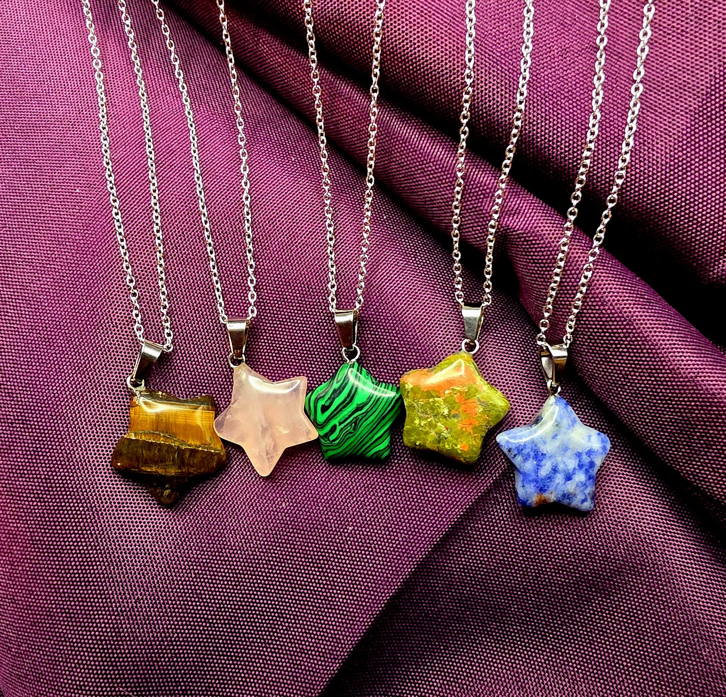 Selection of five hand-carved natural mineral star pendants, featuring polished Tiger's Eye, Rose Quartz, Malachite, Unakite, and Sodalite specimens on silver link chains.