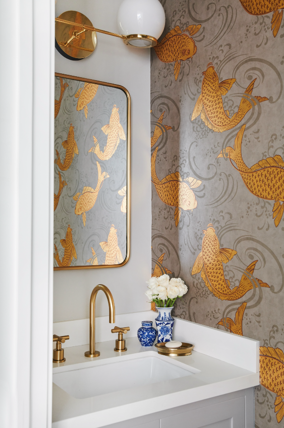 Westchester powder room with gold fixtures, a mirror, a wall sconce, and wallpaper featuring goldfish in orange and gold colors.